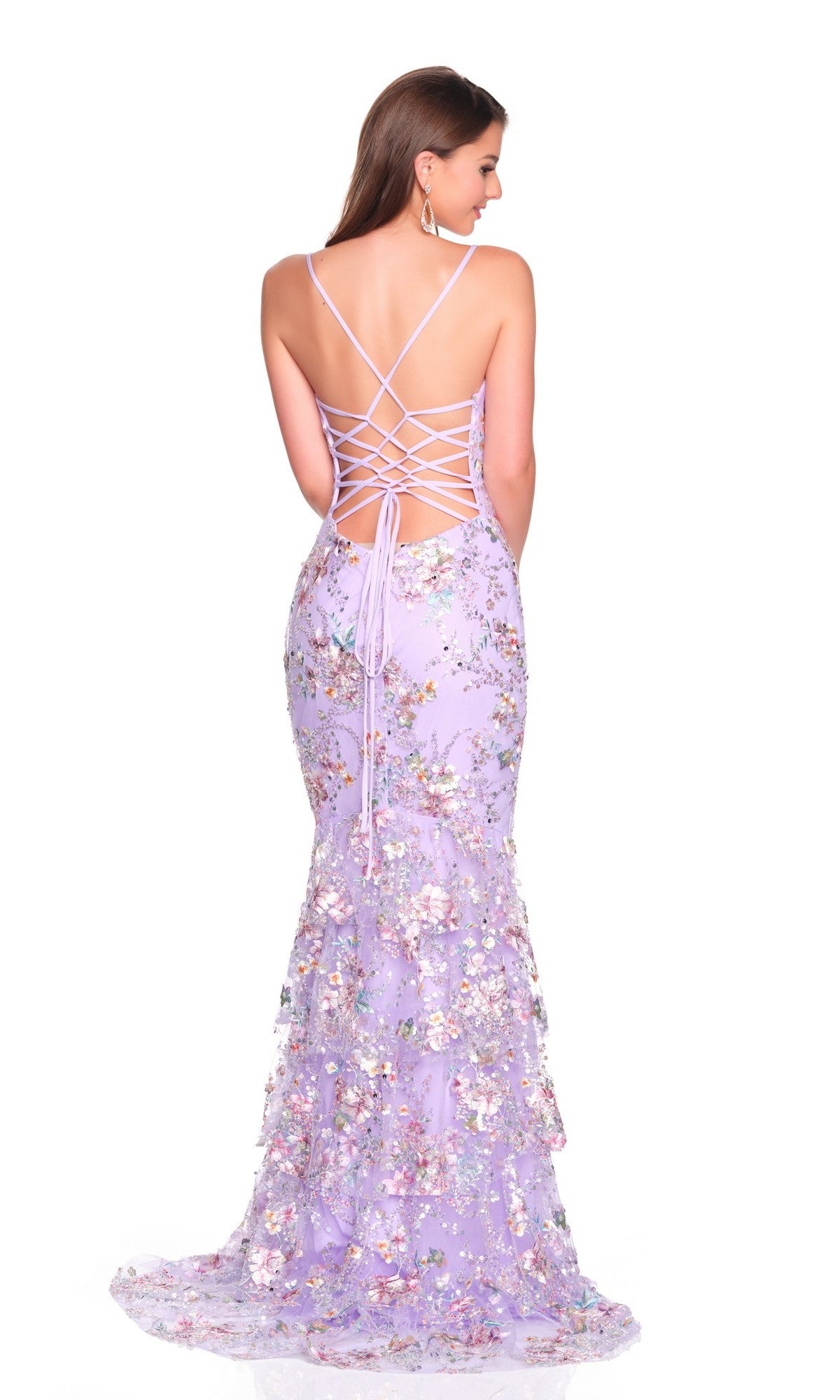 A woman stands facing away against a white background, wearing the Dave and Johnny 12784 long prom dress—a purple gown with floral embellishments and an open, lace-up back.